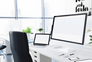 パソコンやタブレット、スマートフォンなど、様々なデバイスが机に置かれたオフィス